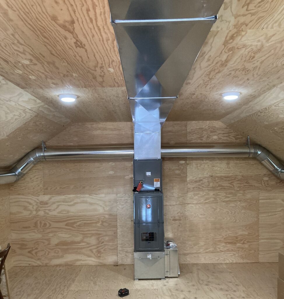 residential furnace and ductwork in clean wood attic space