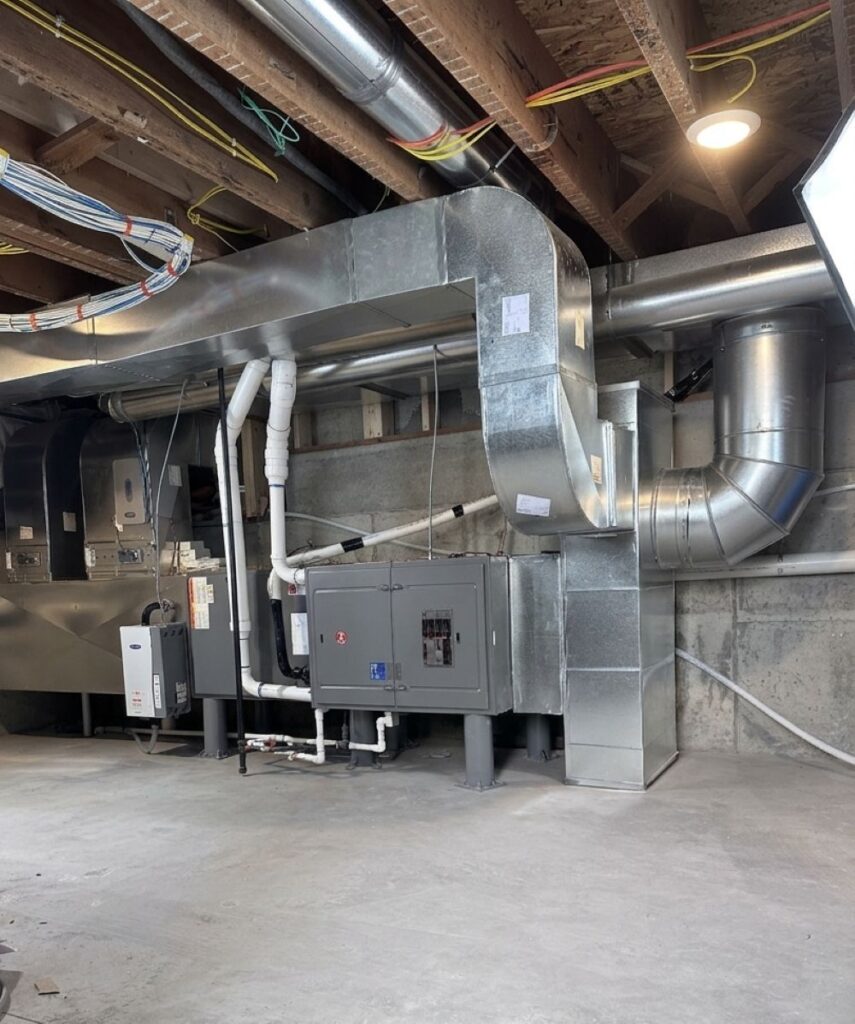 Commercial HVAC ductwork and mechanical equipment installed in a utility room.